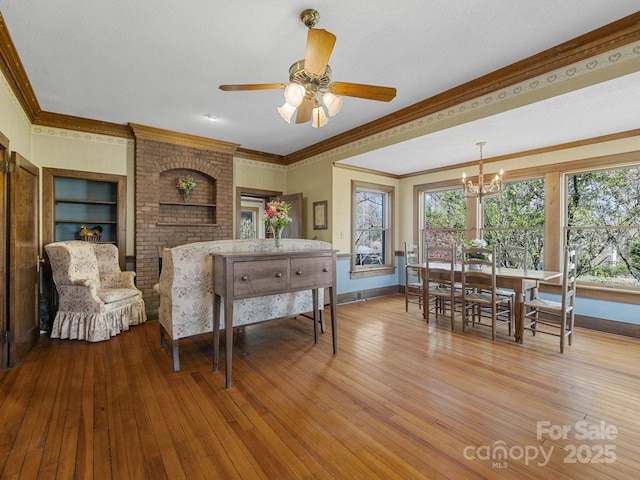 dining room with hardwood / wood-style floors, ceiling fan with notable chandelier, crown molding, and baseboards