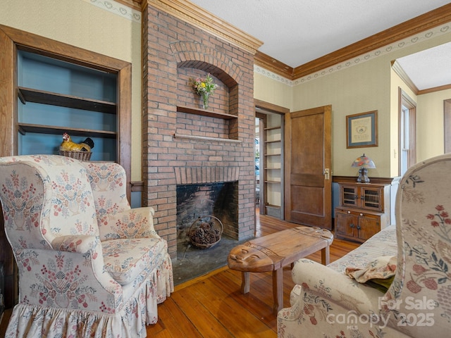 living area with crown molding, built in features, a brick fireplace, and hardwood / wood-style flooring