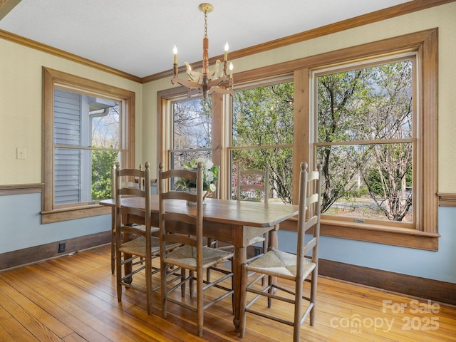 dining room with a chandelier, crown molding, baseboards, and hardwood / wood-style flooring