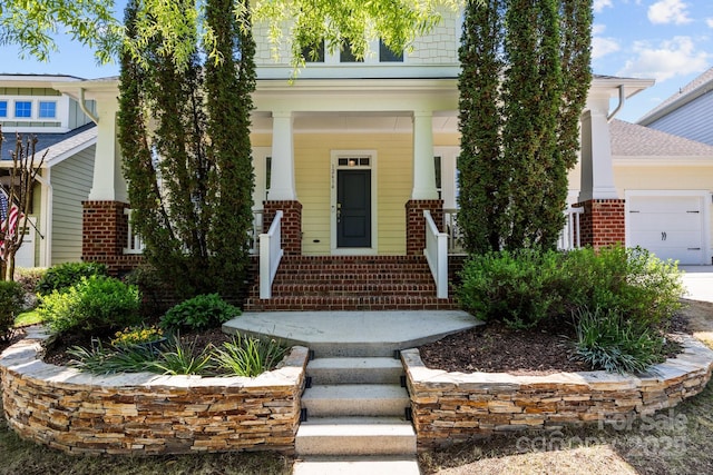 view of front of house featuring a porch, a garage, and brick siding