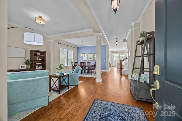 entryway with crown molding, decorative columns, and wood finished floors
