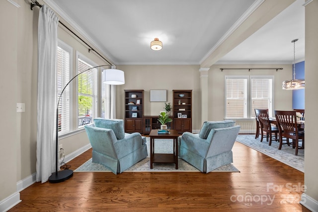 living area featuring crown molding, wood finished floors, and a healthy amount of sunlight