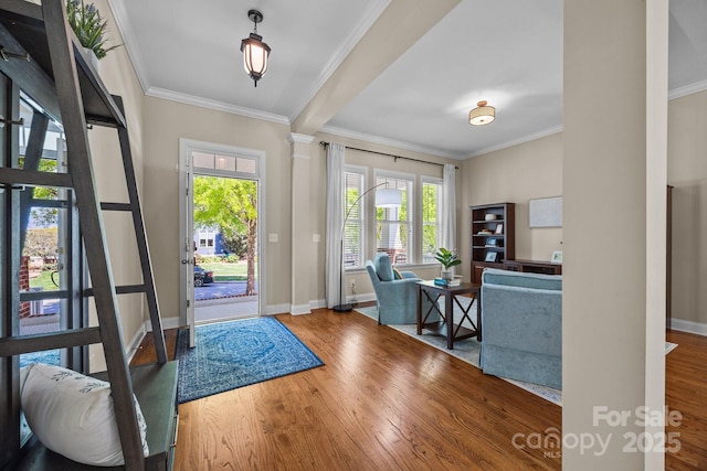 foyer entrance with wood finished floors, decorative columns, baseboards, and ornamental molding
