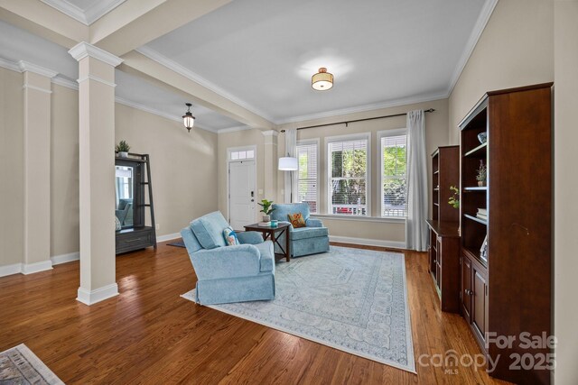 living room with ornate columns, baseboards, ornamental molding, and wood finished floors