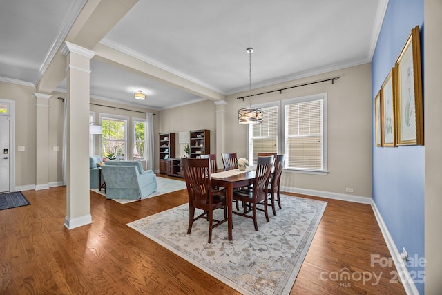 dining room with decorative columns, baseboards, ornamental molding, and wood finished floors