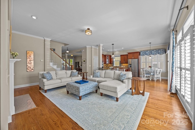 living room featuring baseboards, light wood-style floors, crown molding, recessed lighting, and stairway