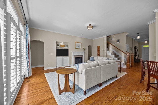living room featuring stairway, light wood-type flooring, crown molding, and a premium fireplace