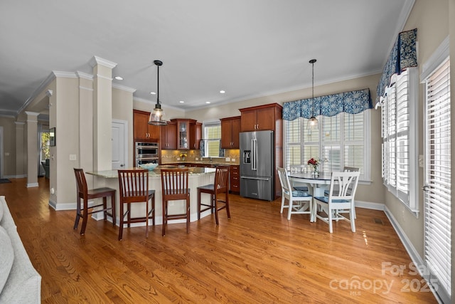 kitchen with glass insert cabinets, a kitchen bar, decorative backsplash, appliances with stainless steel finishes, and light wood finished floors
