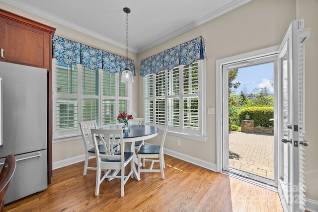 dining area featuring baseboards, light wood-type flooring, and crown molding