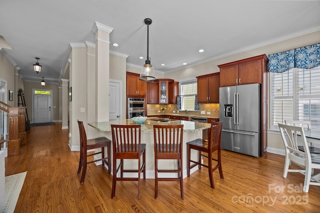 kitchen with light wood-style floors, decorative backsplash, light stone counters, and appliances with stainless steel finishes