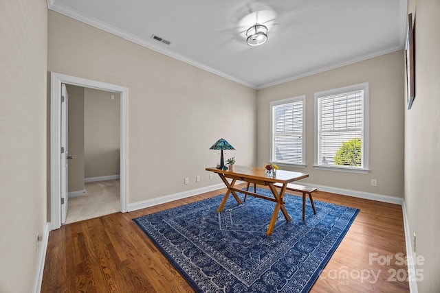 office space with visible vents, ornamental molding, baseboards, and wood finished floors
