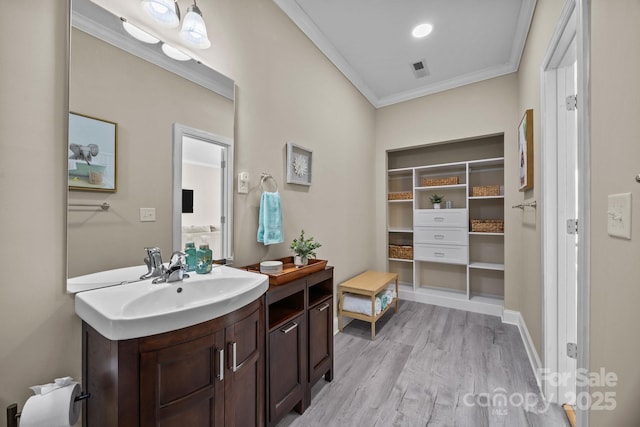 full bathroom featuring vanity, baseboards, ornamental molding, visible vents, and wood finished floors