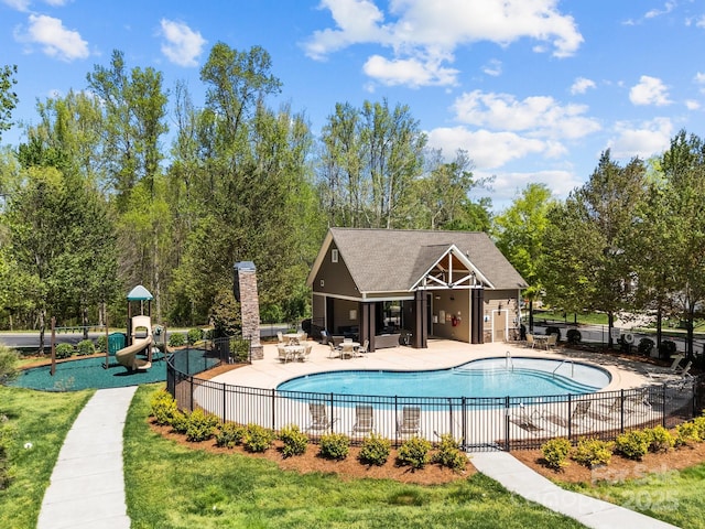 community pool with an outdoor structure, fence, a patio, and playground community