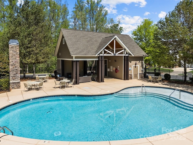 pool featuring a patio, fence, an exterior structure, and an outdoor structure