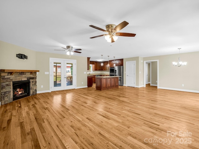 575 Hill Rd, Lincolnton, NC 28092 - unfurnished living room with ceiling fan with notable chandelier, baseboards, a stone fireplace, and light wood-style flooring