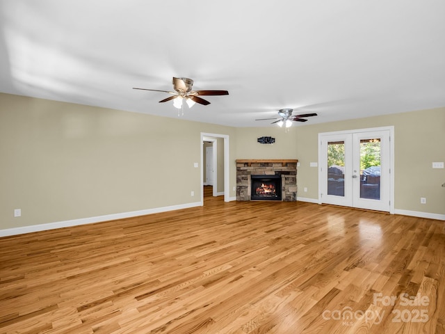 575 Hill Rd, Lincolnton, NC 28092 - unfurnished living room featuring baseboards, a stone fireplace, ceiling fan, french doors, and light wood finished floors