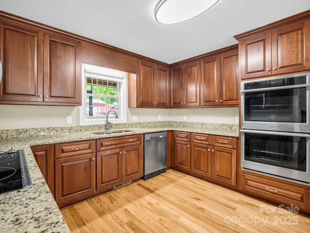 575 Hill Rd, Lincolnton, NC 28092 - kitchen featuring brown cabinets, light stone countertops, a sink, light wood-style floors, and stainless steel appliances