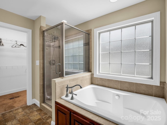 575 Hill Rd, Lincolnton, NC 28092 - full bathroom featuring visible vents, baseboards, a bath, a spacious closet, and a stall shower