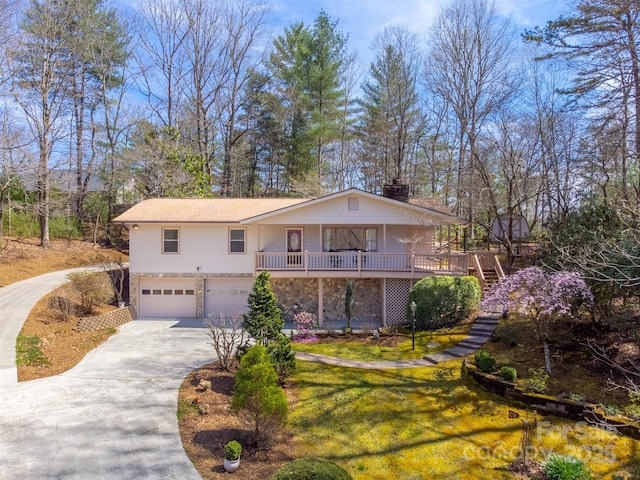 view of front of home with driveway, an attached garage, stairs, a porch, and a front yard