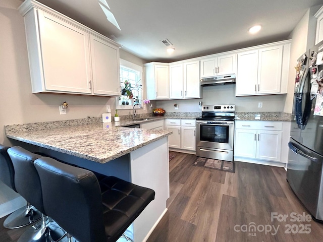 kitchen featuring a peninsula, white cabinetry, under cabinet range hood, appliances with stainless steel finishes, and a sink
