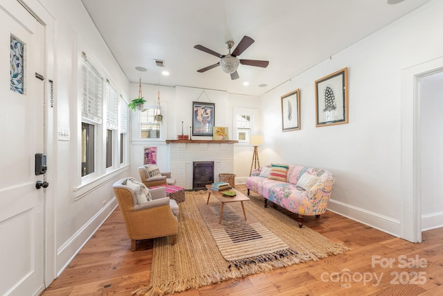living room with a fireplace, baseboards, a ceiling fan, and wood finished floors