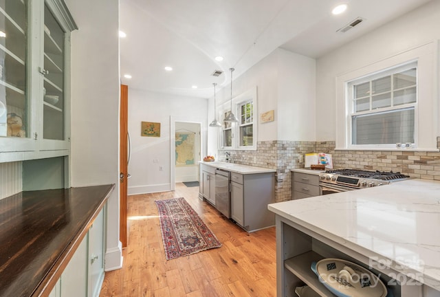 kitchen with light wood-type flooring, gray cabinets, light stone countertops, visible vents, and stainless steel appliances