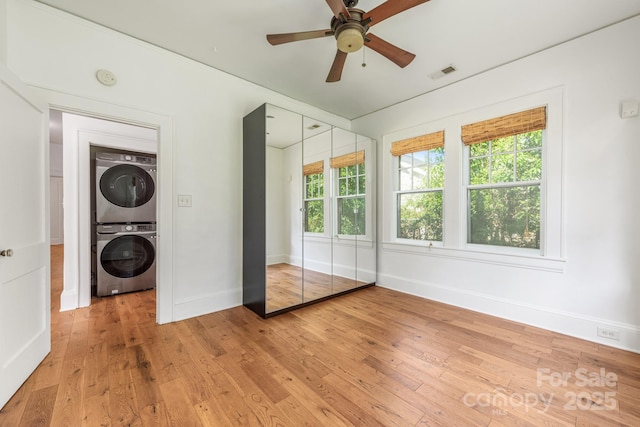 laundry room with baseboards, light wood-style flooring, stacked washer / dryer, laundry area, and visible vents