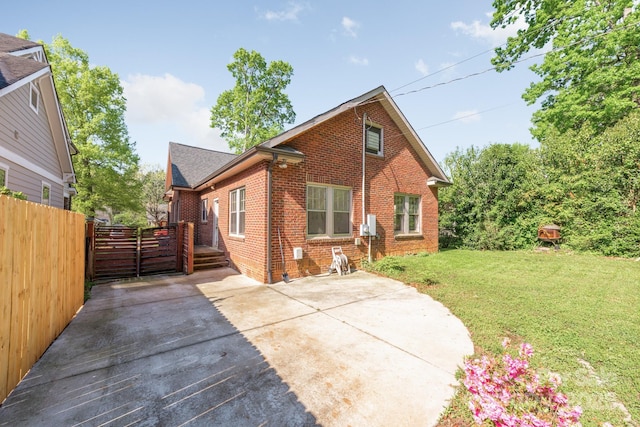 rear view of house with a yard, a patio area, fence, brick siding, and a shingled roof