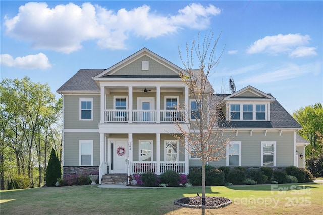 view of front of property with covered porch, a ceiling fan, a front lawn, and a balcony