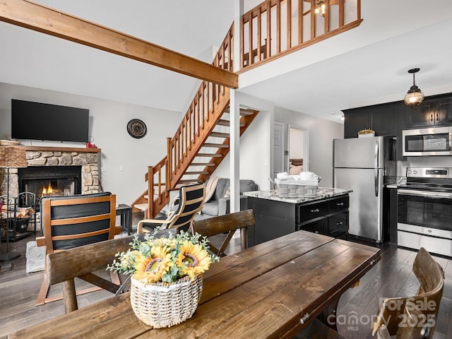 dining area with stairs, a high ceiling, dark wood-style floors, and a fireplace