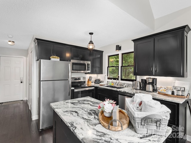 kitchen with stainless steel appliances, light stone counters, dark cabinets, and a sink