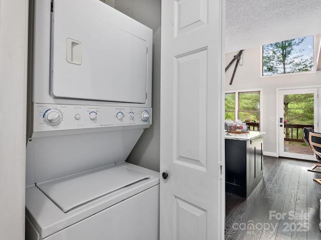 washroom featuring stacked washer and dryer, laundry area, dark wood-style floors, and baseboards