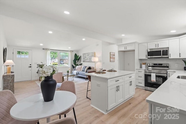 3423 Archer Ave, Charlotte, NC 28217 - kitchen featuring stainless steel appliances, light wood finished floors, white cabinets, recessed lighting, and vaulted ceiling