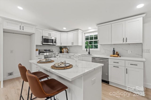 3423 Archer Ave, Charlotte, NC 28217 - kitchen with appliances with stainless steel finishes, a sink, white cabinetry, tasteful backsplash, and a breakfast bar