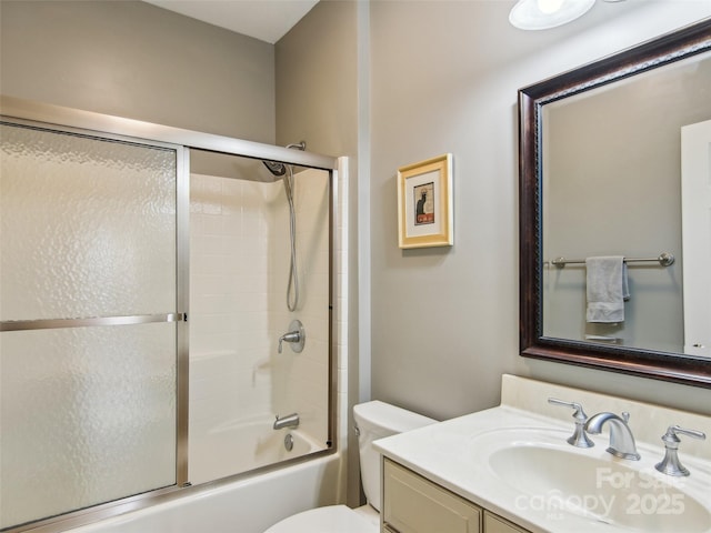 full bath with toilet, vanity, and bath / shower combo with glass door