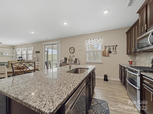 807 Oak Manor Dr SE, Concord, NC 28025 - kitchen with light wood-style floors, visible vents, a center island with sink, appliances with stainless steel finishes, and a sink