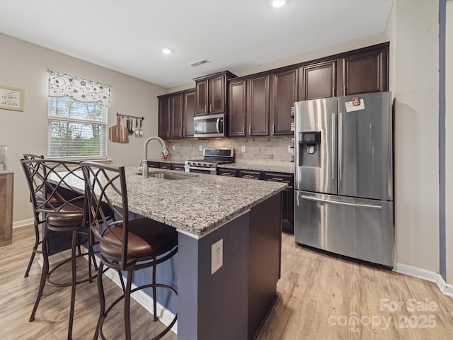 807 Oak Manor Dr SE, Concord, NC 28025 - kitchen with dark brown cabinetry, backsplash, a kitchen bar, appliances with stainless steel finishes, and a sink