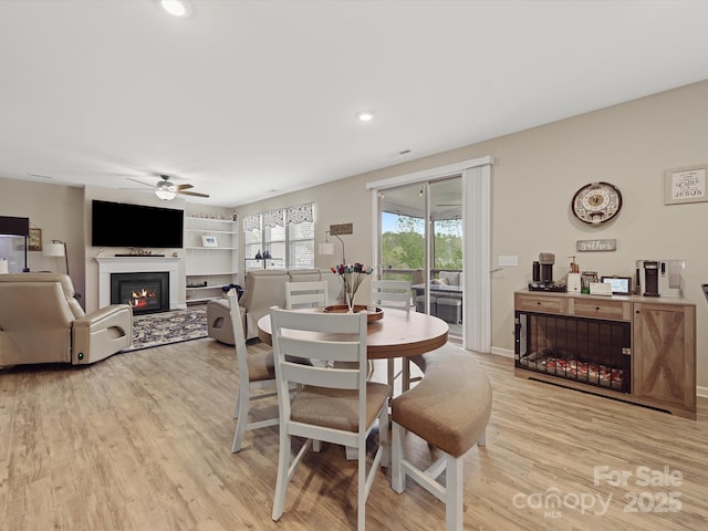 807 Oak Manor Dr SE, Concord, NC 28025 - dining space featuring light wood-style floors, a ceiling fan, a glass covered fireplace, recessed lighting, and baseboards