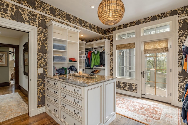 walk in closet featuring a notable chandelier and dark wood-style floors