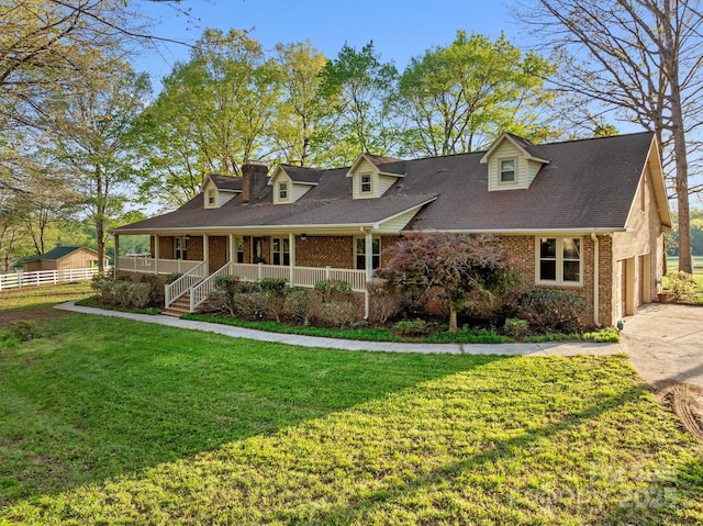 cape cod home featuring driveway, a front yard, brick siding, fence, and covered porch