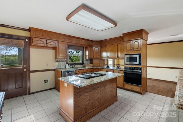 kitchen featuring a sink, light tile patterned floors, black appliances, and brown cabinets