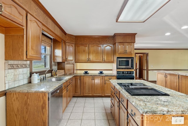 kitchen with black appliances, a kitchen island, light stone counters, light tile patterned flooring, and a sink