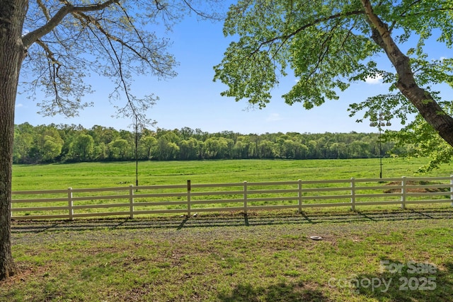 view of yard with a forest view, fence, and a rural view