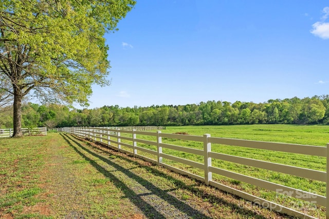 view of yard with a forest view, fence, and a rural view