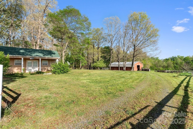 view of yard with an outbuilding, a detached garage, and fence
