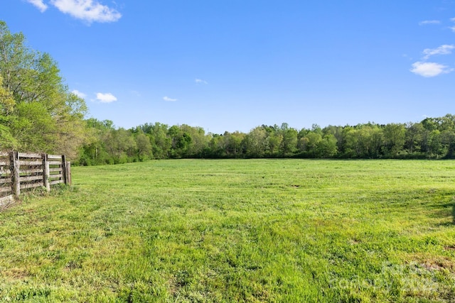 view of yard with a view of trees, fence, and a rural view