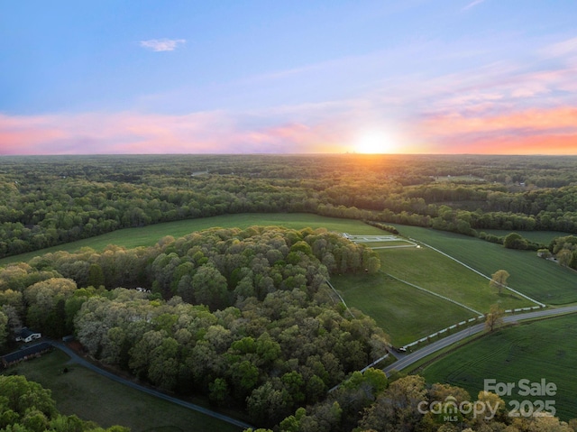 aerial view at dusk with a wooded view and a rural view