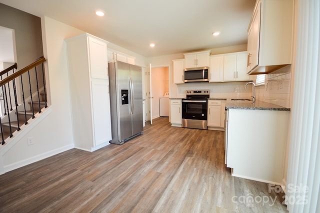 52 Cain Hollow Way, Asheville, NC 28806 - kitchen featuring stainless steel appliances, light wood-style flooring, a sink, dark stone counters, and washer / dryer