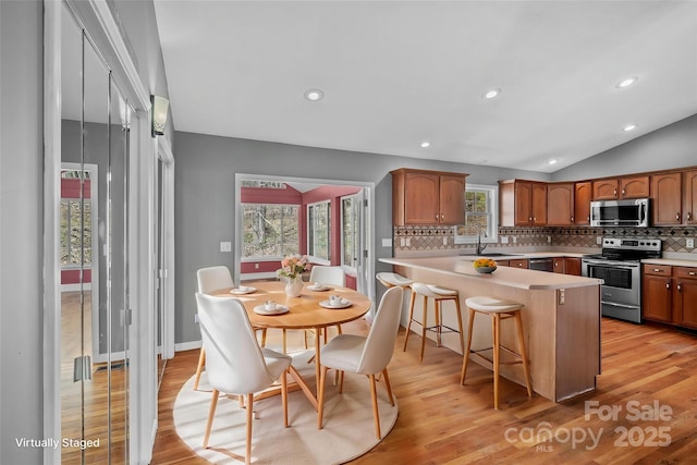 kitchen with light wood-style flooring, decorative backsplash, a peninsula, and stainless steel appliances