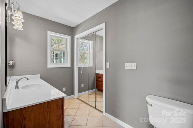 bathroom with toilet, vanity, baseboards, and tile patterned flooring